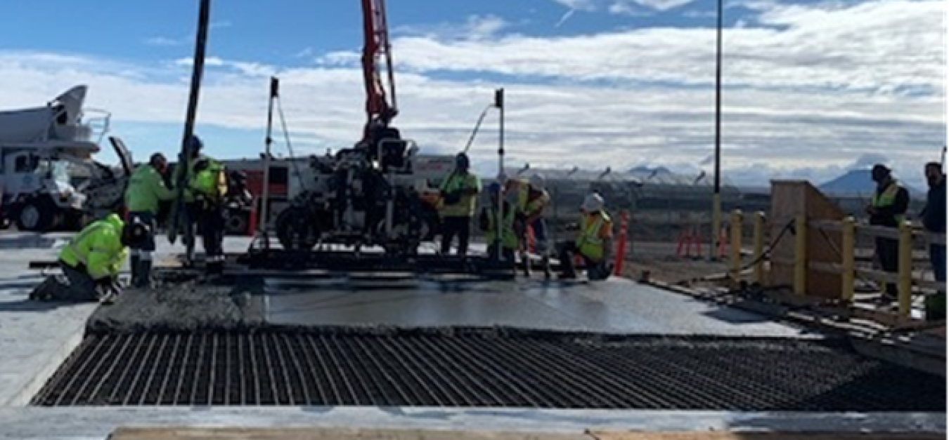 A construction site with lots of employees in safety gear and construction vehicles