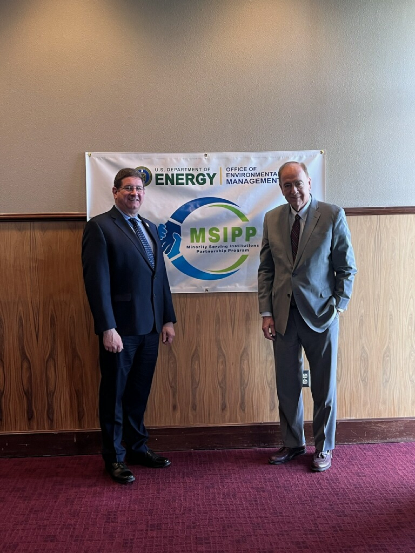 Two leaders pose besides a poster that reads MSIPP