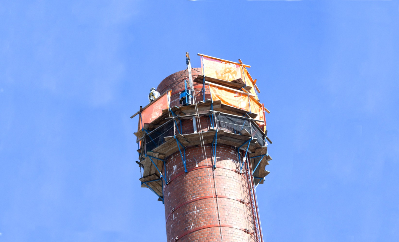 Up close shot of a tall, red, cylinder stack with the blue sky in the background