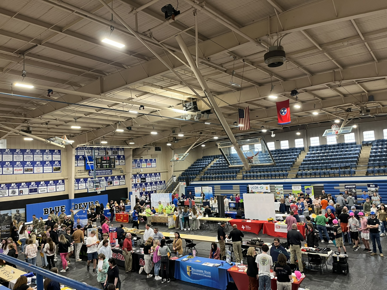 A large gymnasium set up for a career fair with lots of booths and people