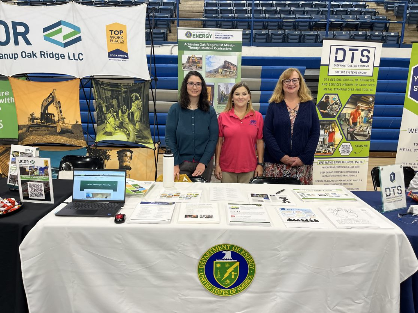 Three women standing behind a table at a career fair day