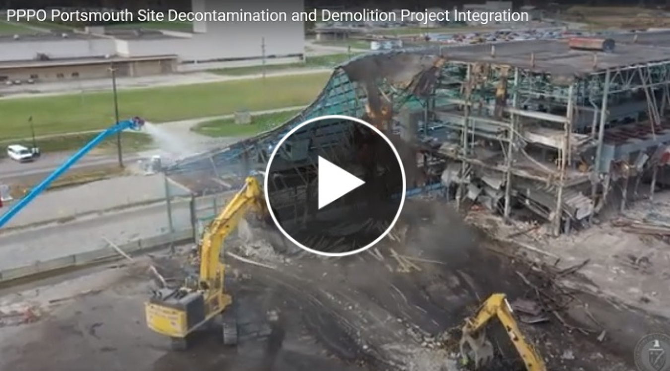 A still shot from a video of a construction sites and vehicles with a play button over it