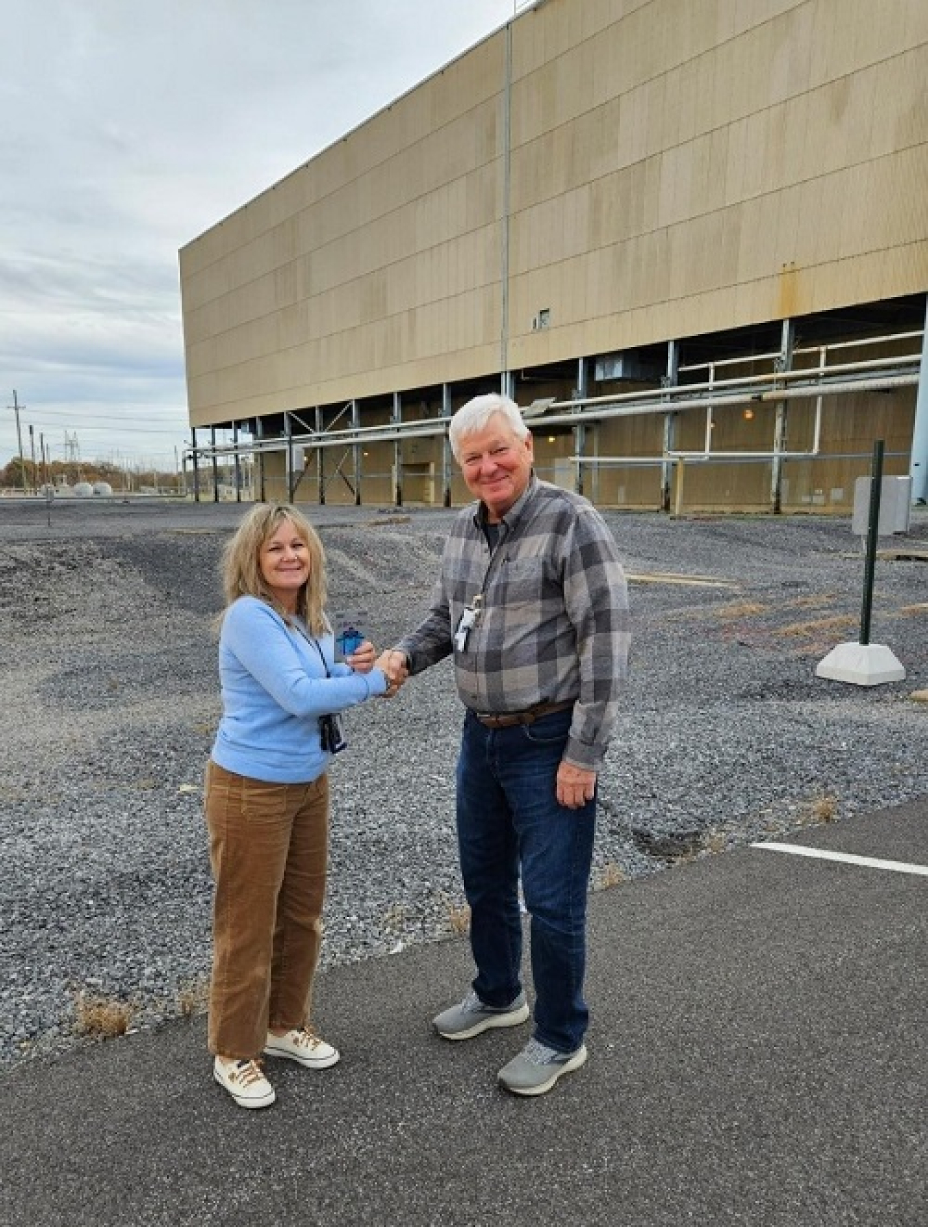 A man and a woman standing outside a building, shaking hands