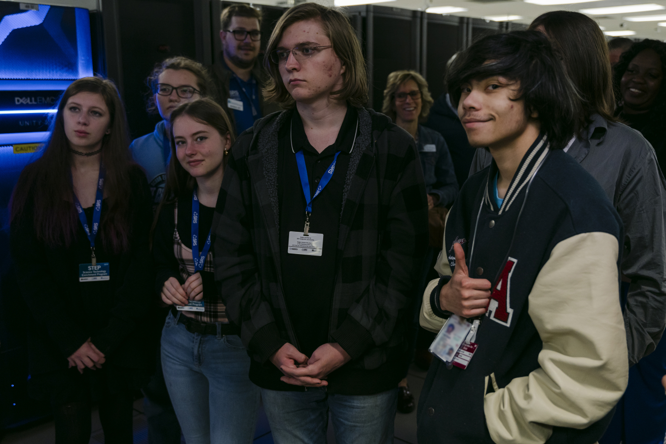 A group of high school students on a tour of a computing facility, listening to the tour guide