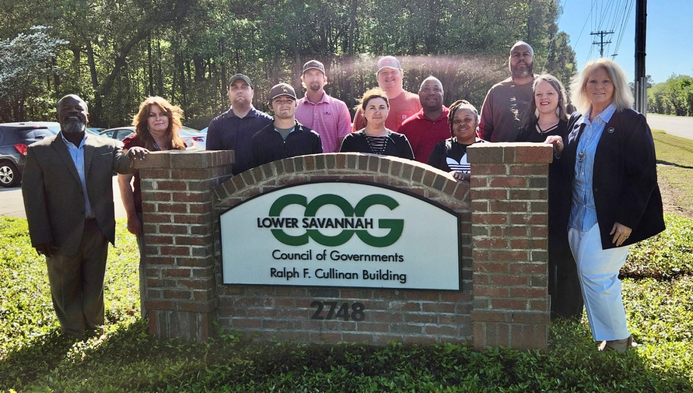 A group of people pose for a picture by a sign that reads Lower Savannah "COG"