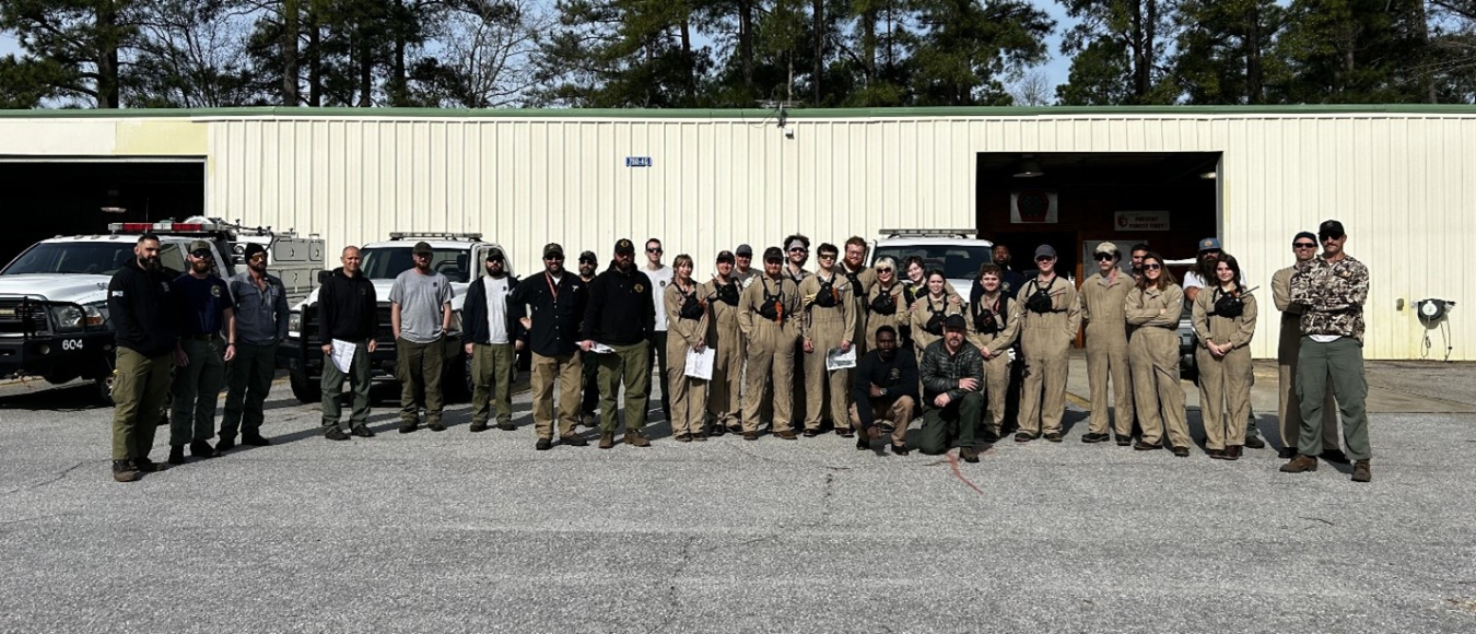 A large group photo of individuals posed in front of a building