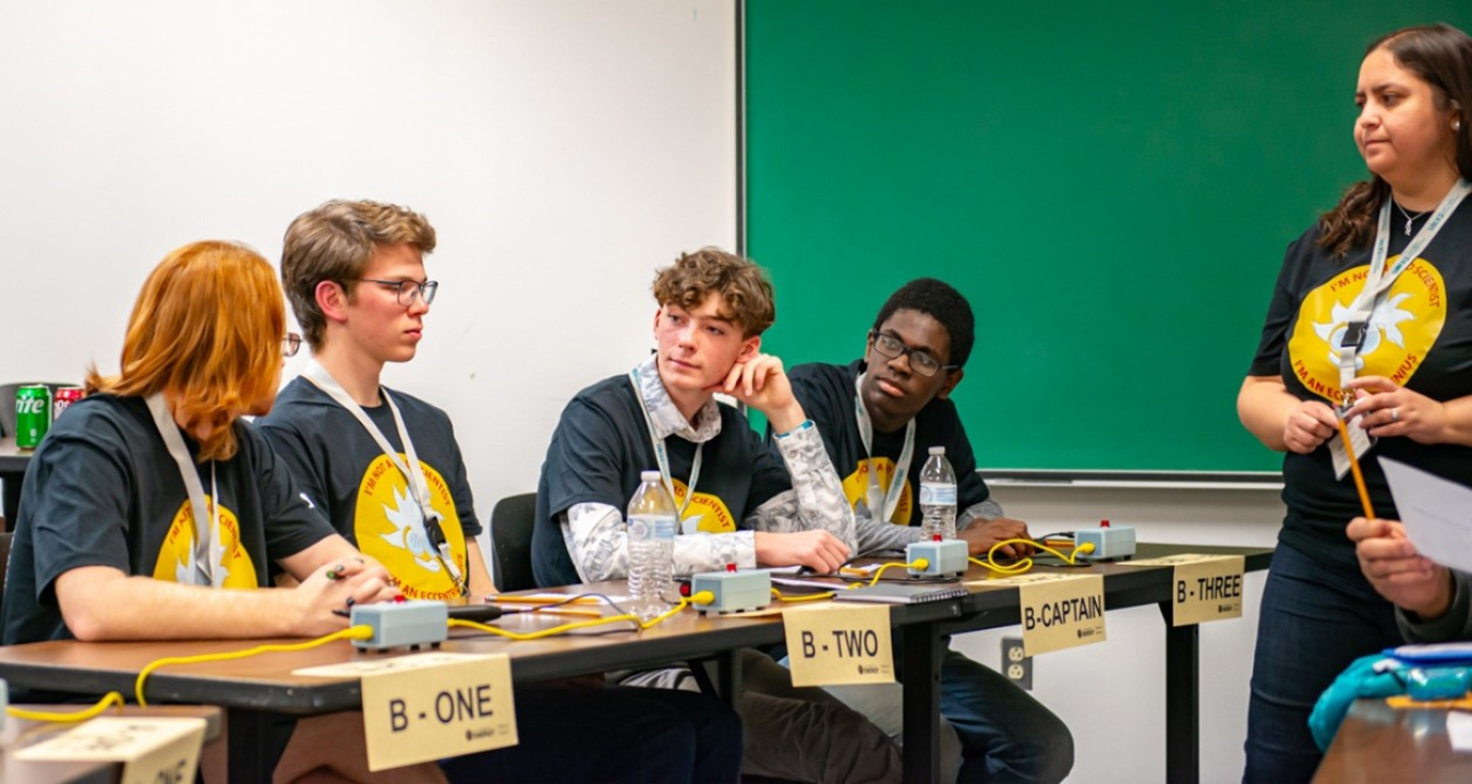 A group of high school students competing in a science bowl sit at a table