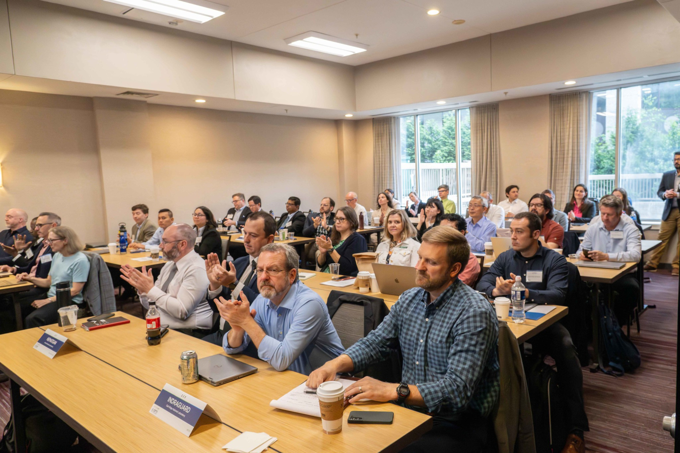 A meeting room full of people at tables, watching presentations. 