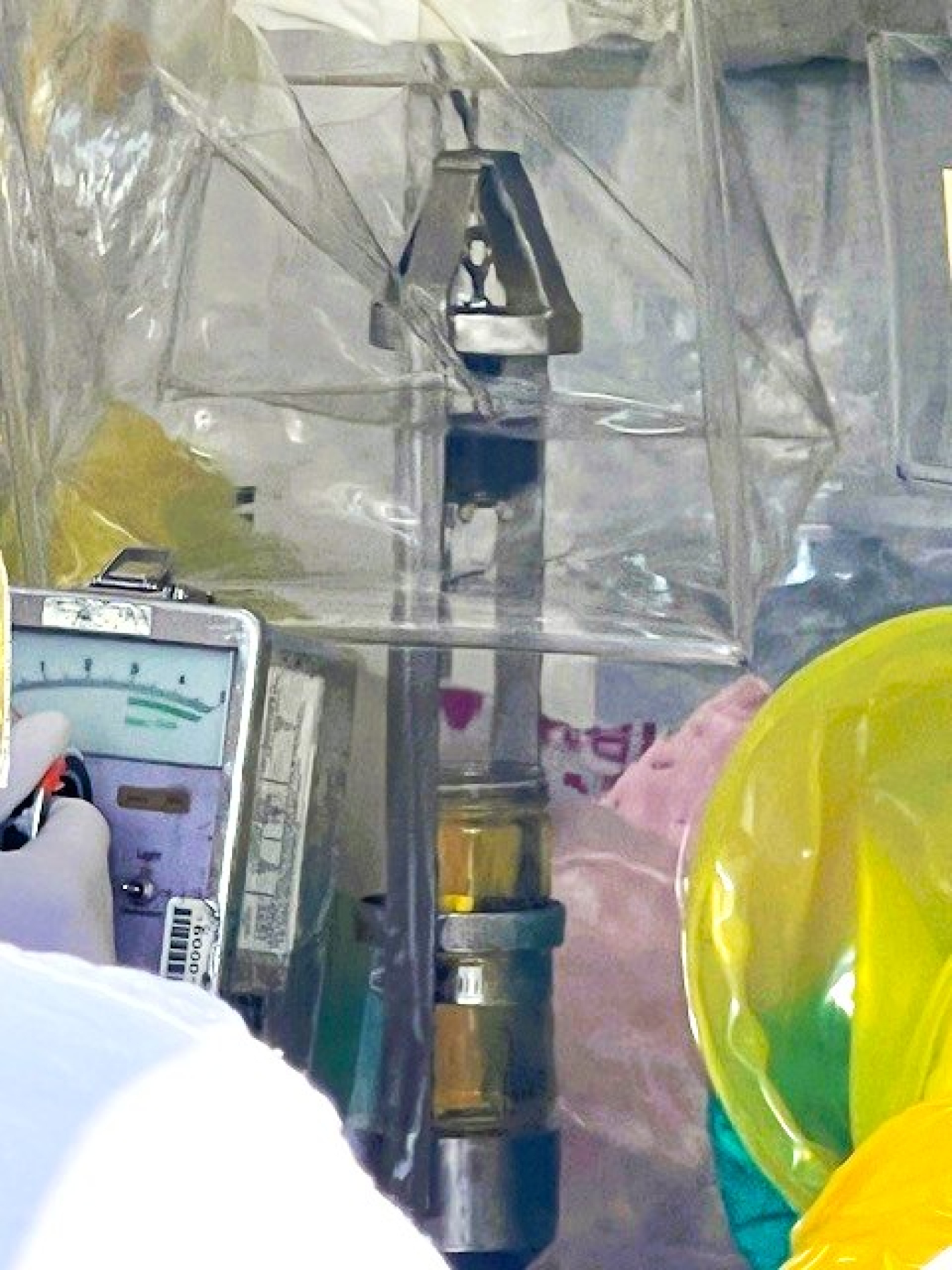 A zoomed in picture of a metal machine inside a plastic covering