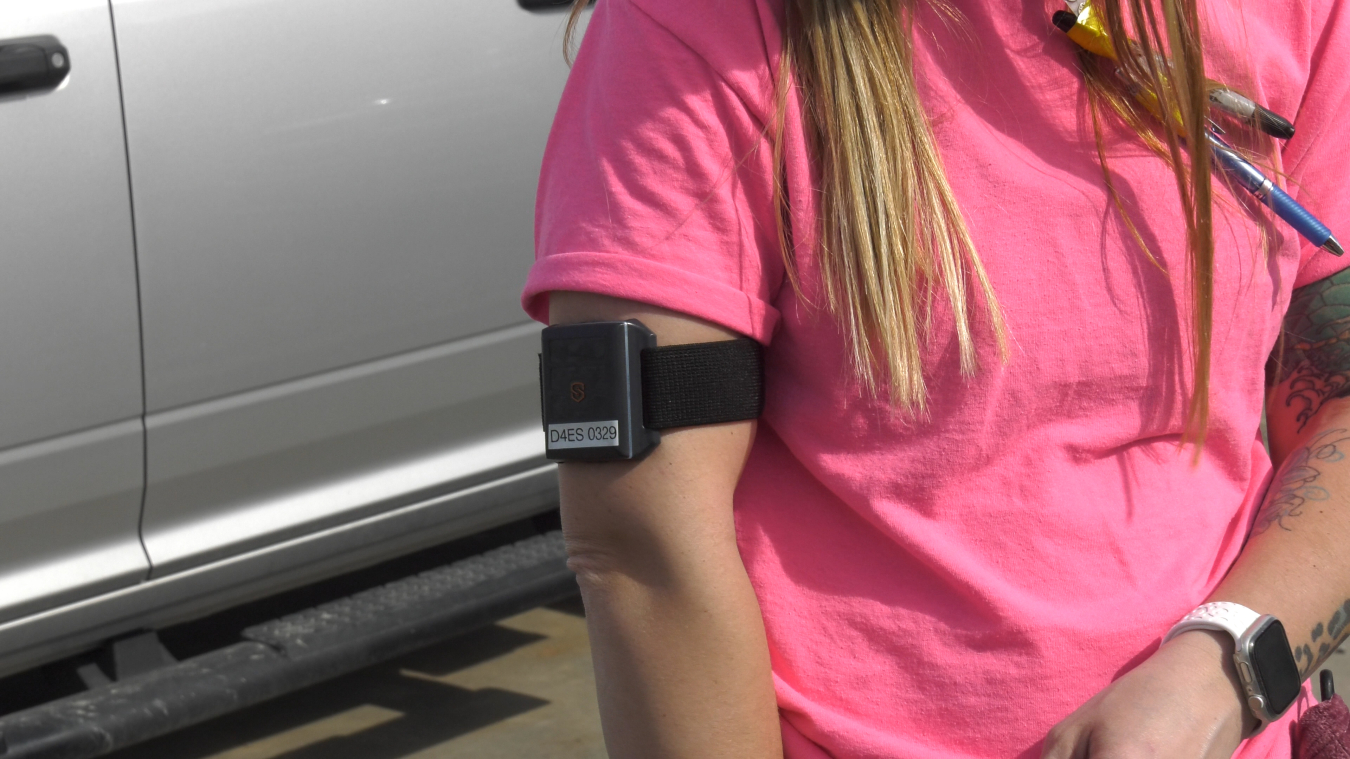 A woman in a pink t-shirt from the neck down with an armband around her arm