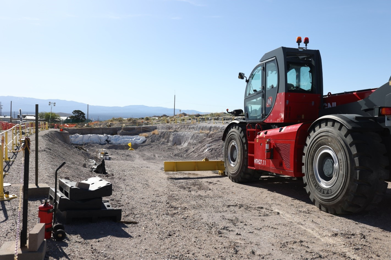 A red work vehicles drives across a path of dirt