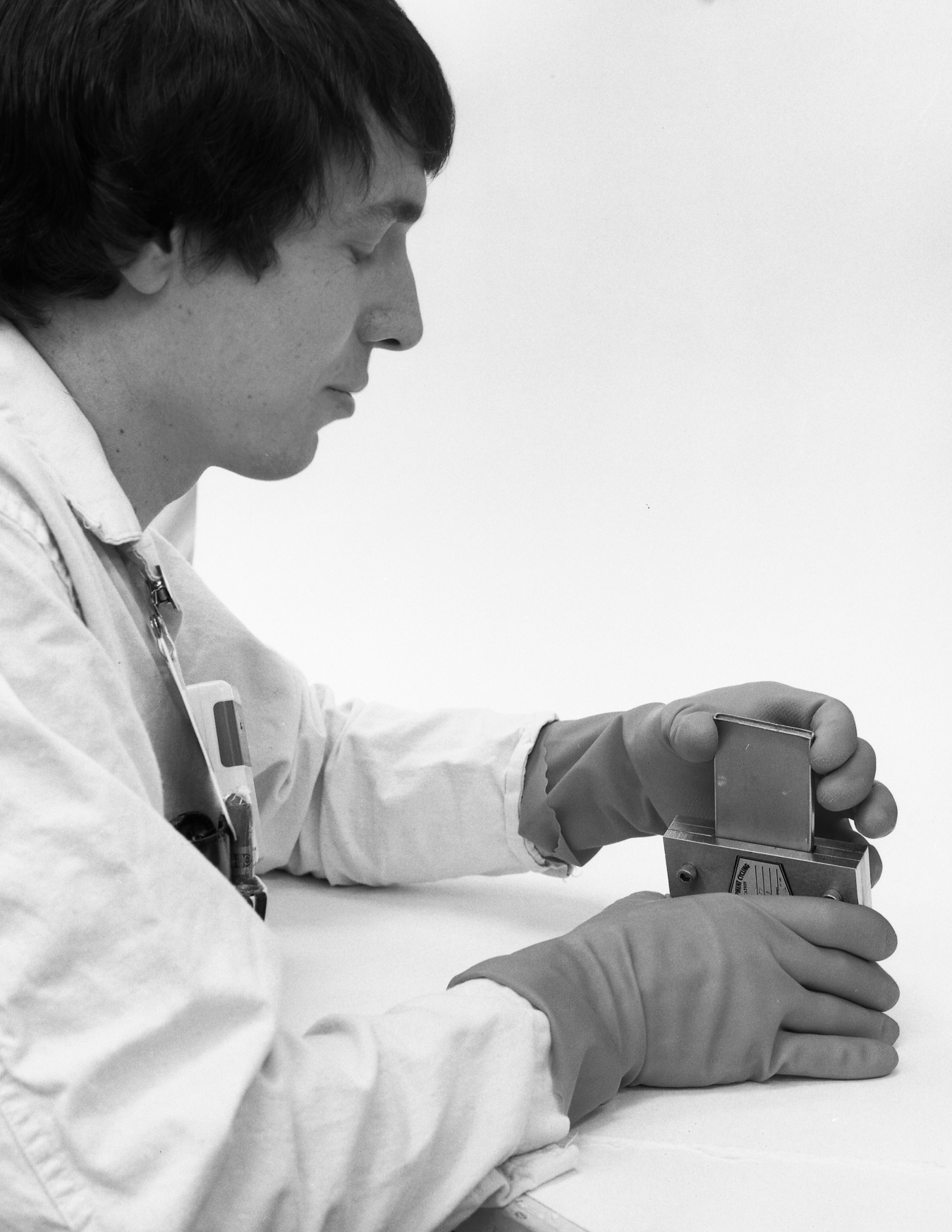 A black and white photo of a man wearing gloves and handling a tool