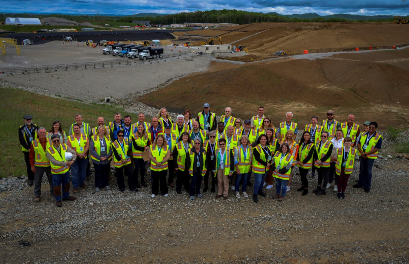 Large group photo of members of a board all wearing yellow safety vests at a construction site