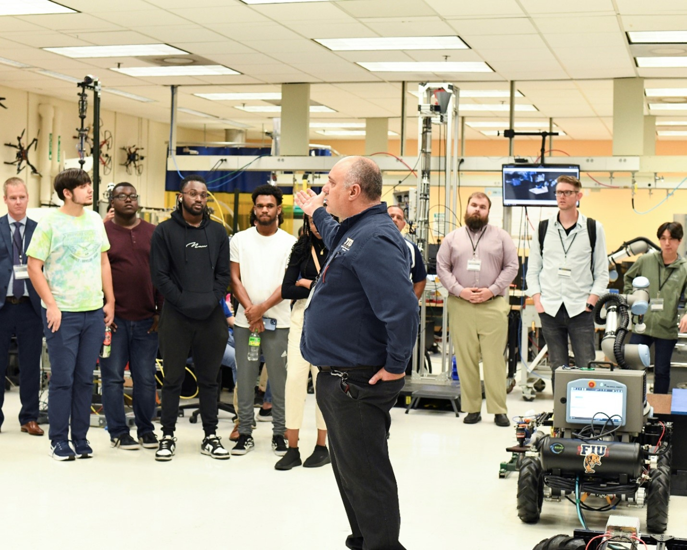A scientist stands in the front of a lab classroom and speaks to college students