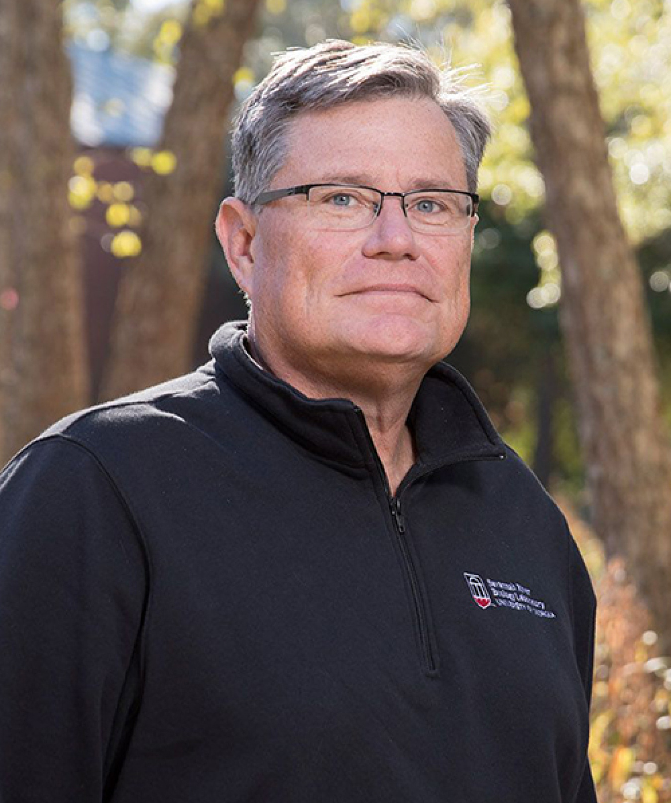 Professional headshot of a man with a black shirt on standing outdoors