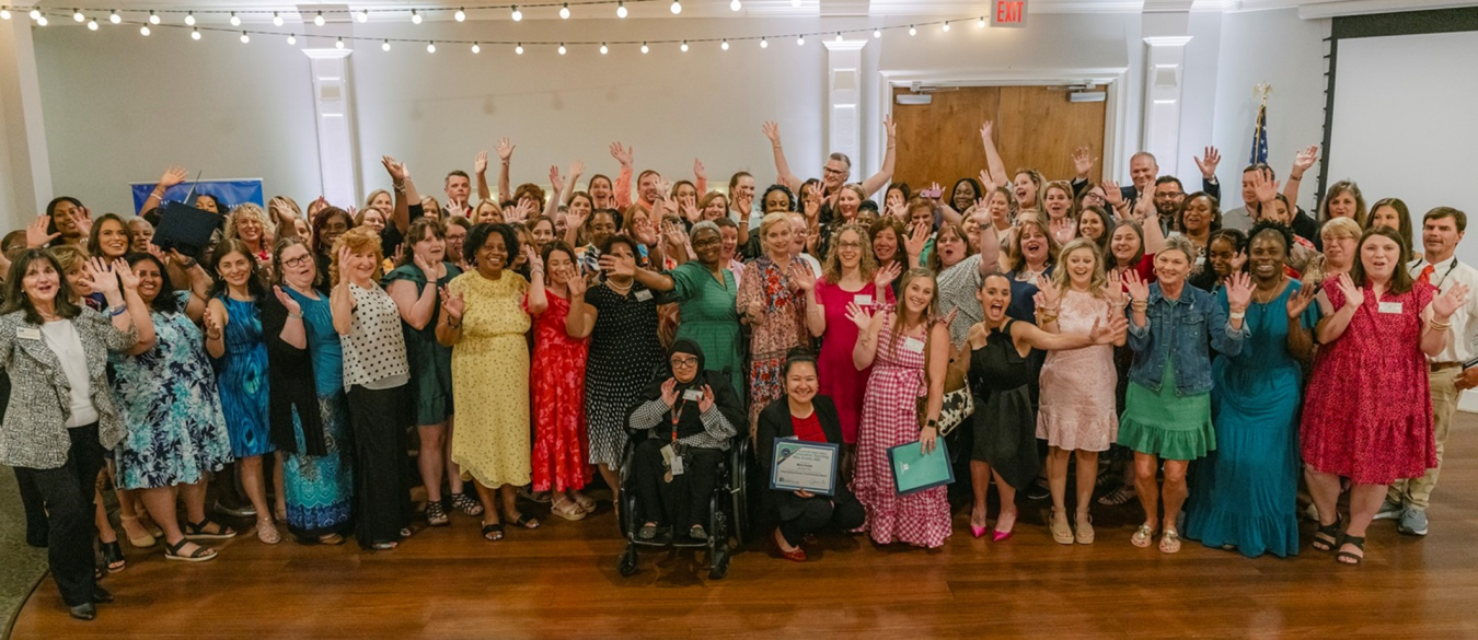 A large group of people inside a ballroom pose for a picture