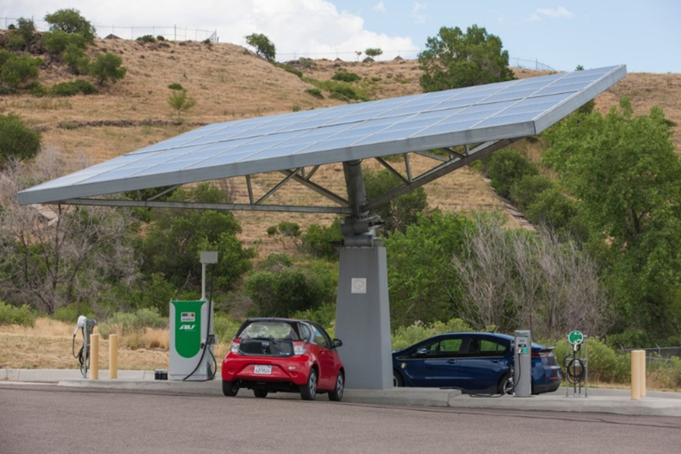 A solar panel on a parking structure with EV charging and two cars underneath.