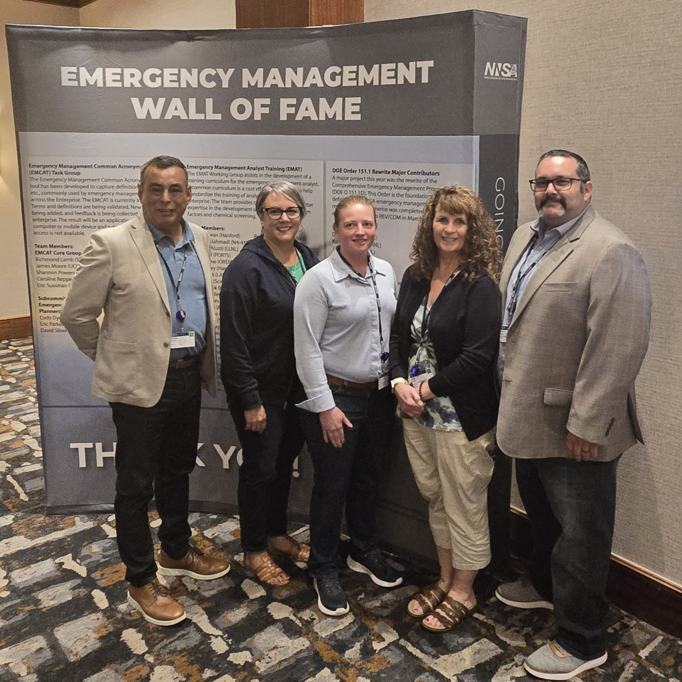 A group of five people pose for a photo at a conference