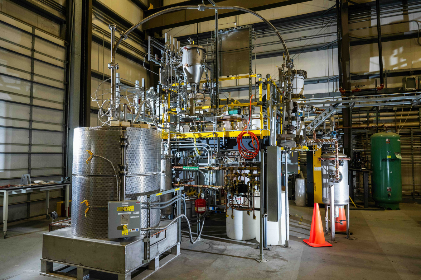 A large pumping system with lots of metal tubes and wires throughout, sitting inside a facility building