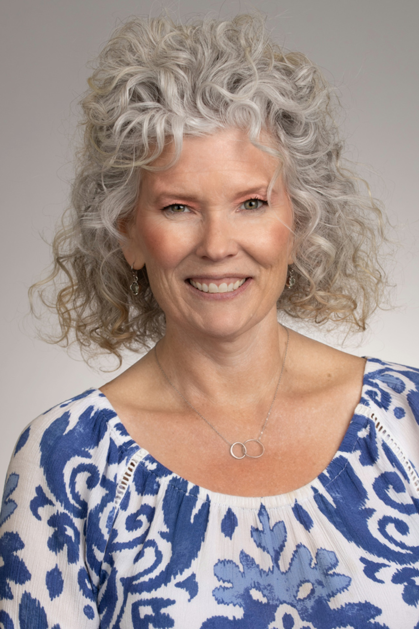 Portrait of a woman with curly grey hair.