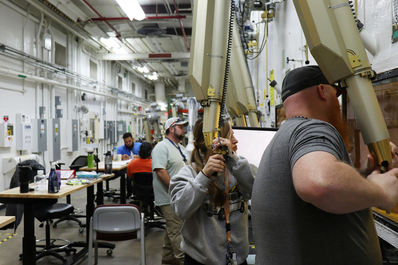 A group of employees working on a machine, some holding golden parts of the machine