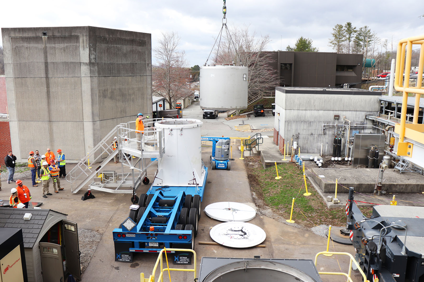 An overhead shot of a waste tank being lifted onto a shipping truck with workers around