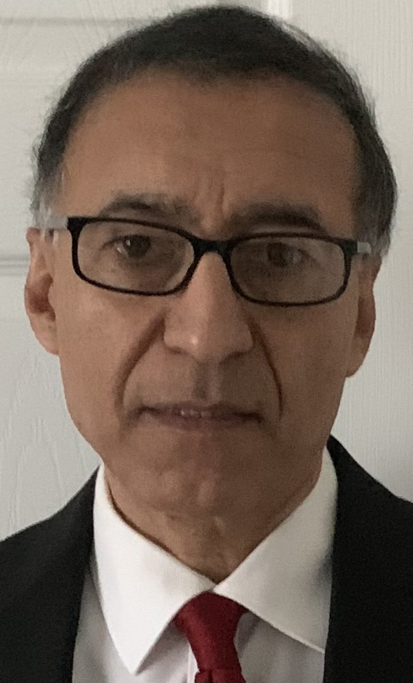 Headshot of a man in a suit wearing glasses