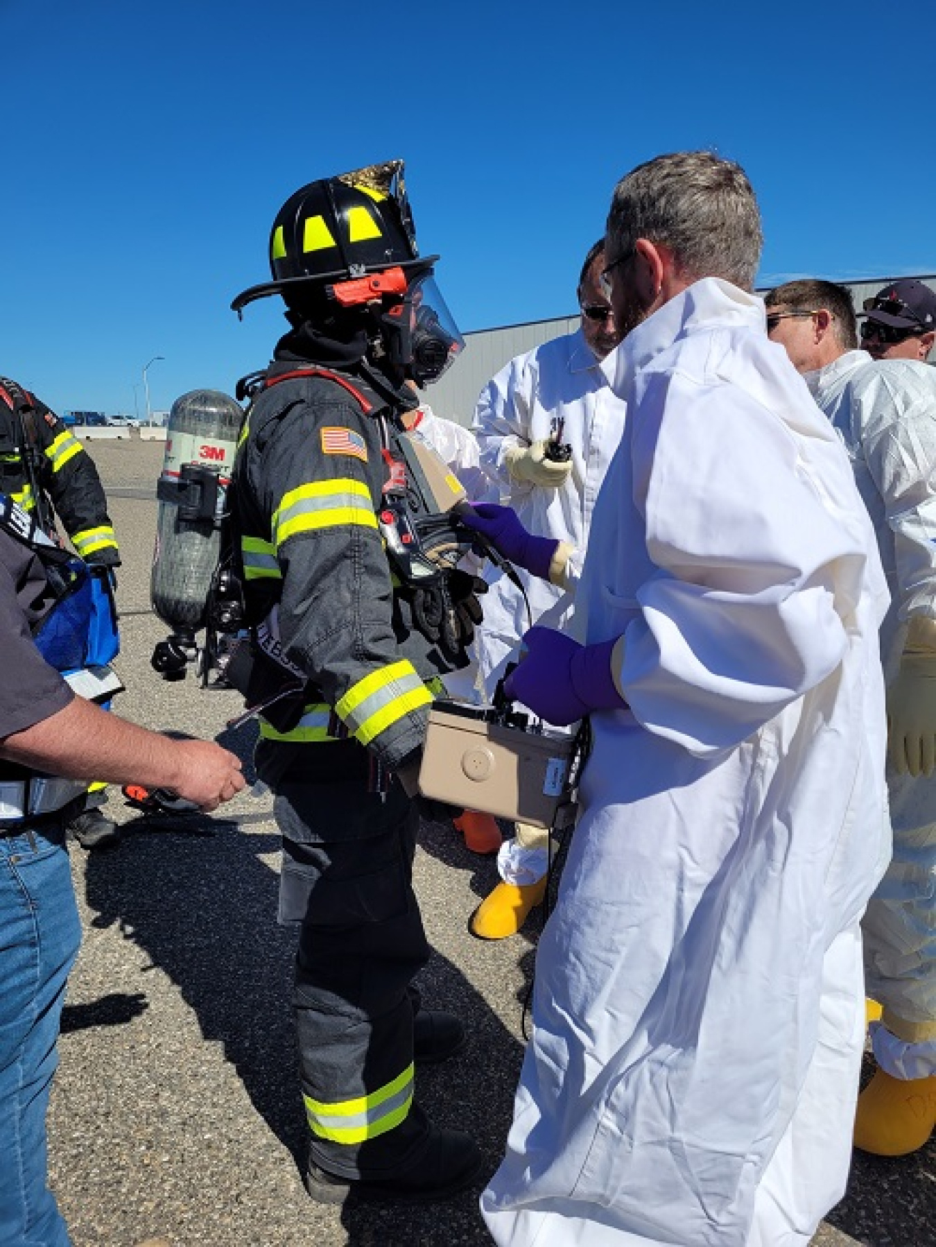 A firefighter stands next to radiological control technicians.