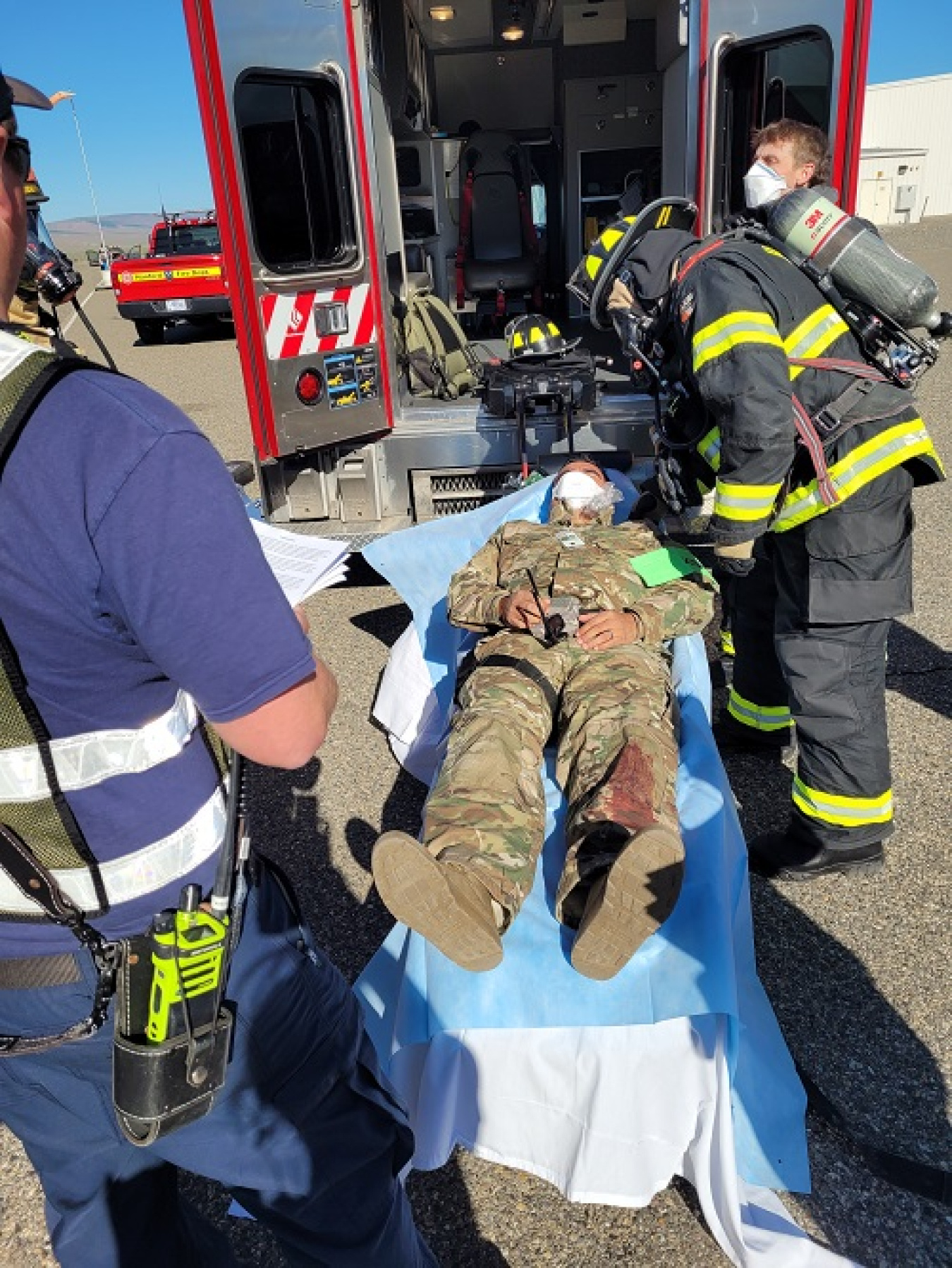 A fire response team simulated wrapping and loading a contaminated and injured worker in an aid car.