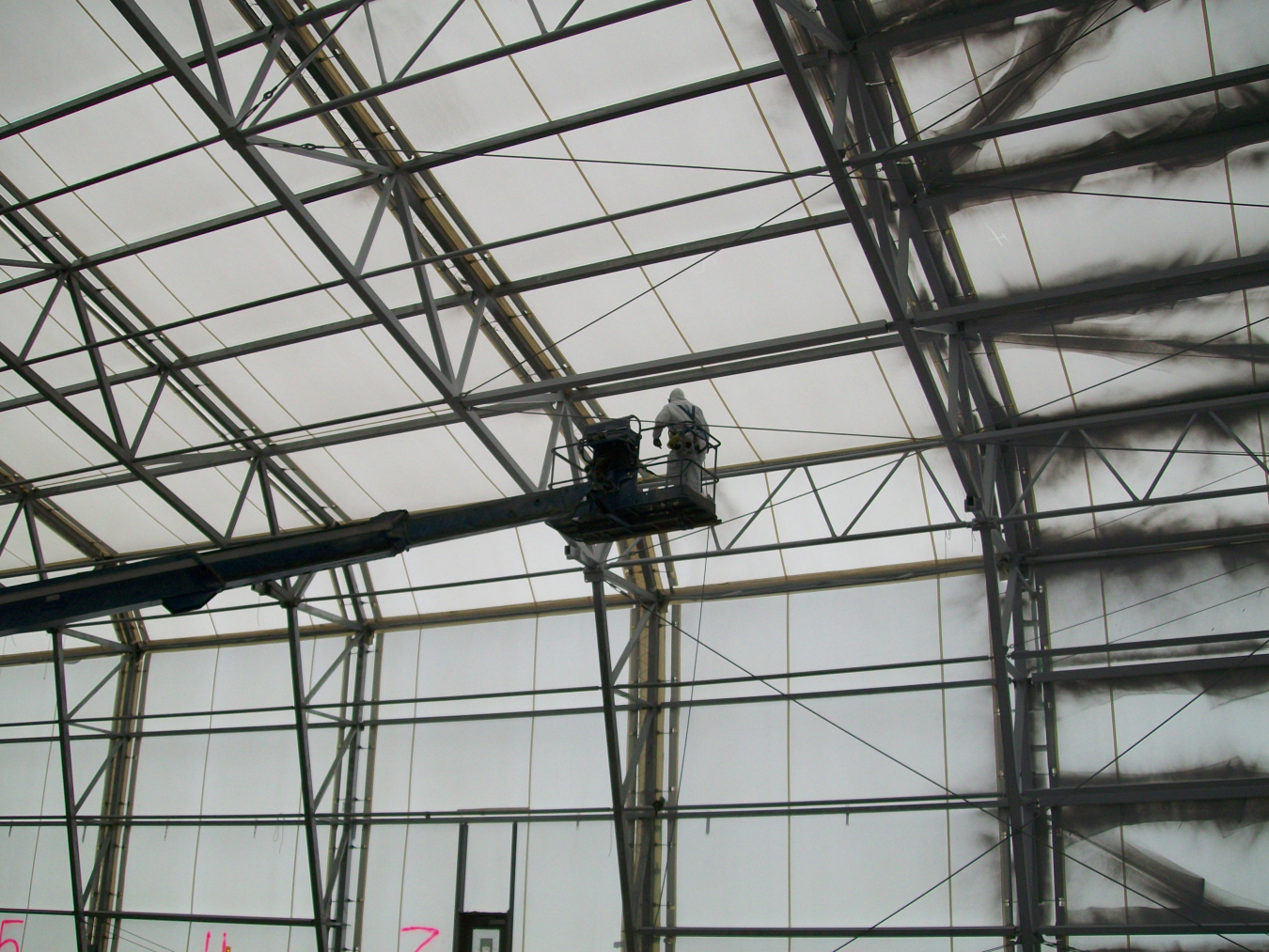 A man inside a large facility building on a crane lift
