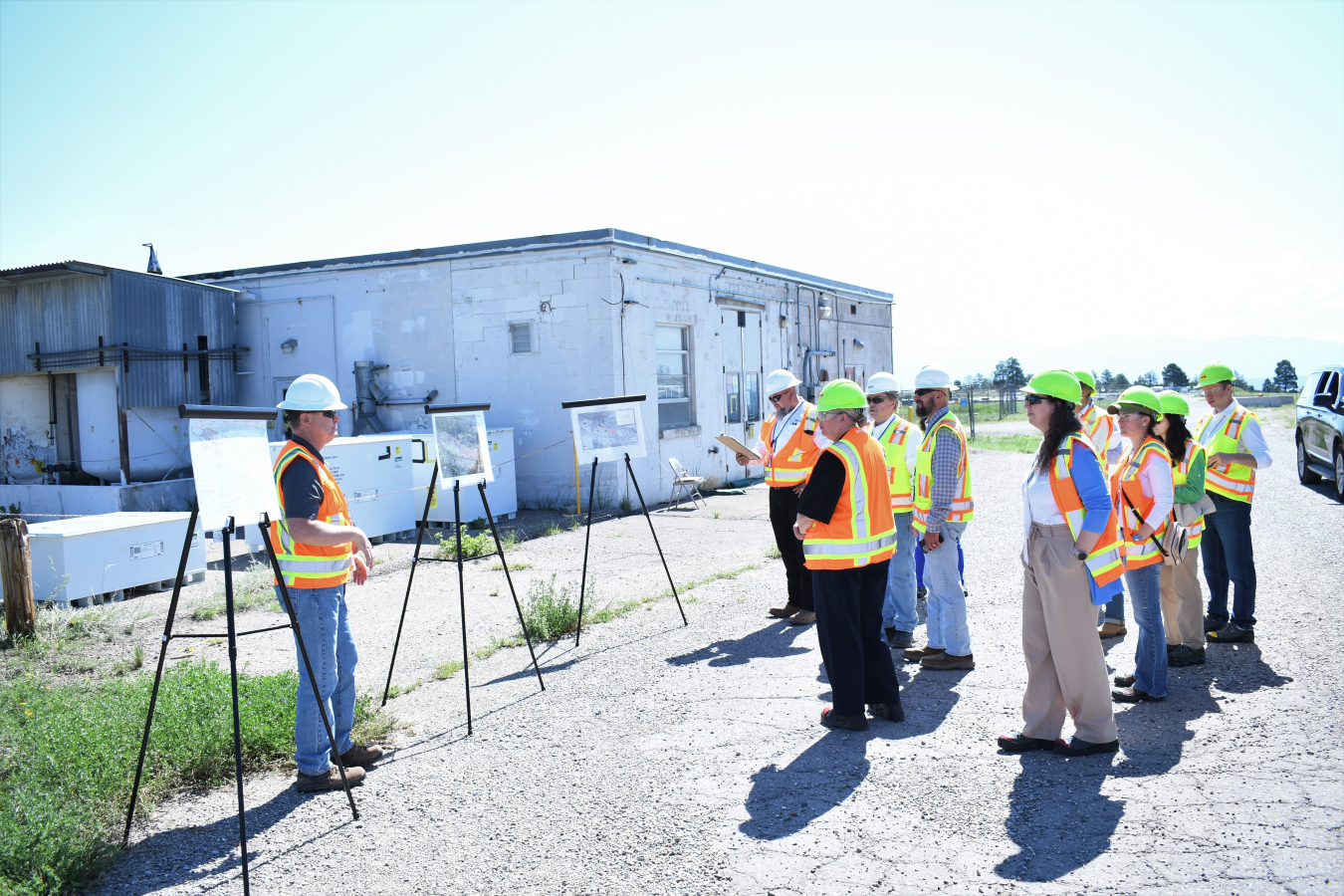 A group of EM leaders in hard hats and protective vests tour a Los Alamos site