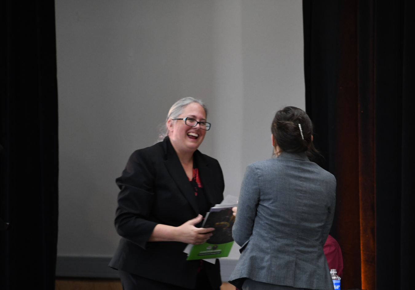 Two women smile and shake hands
