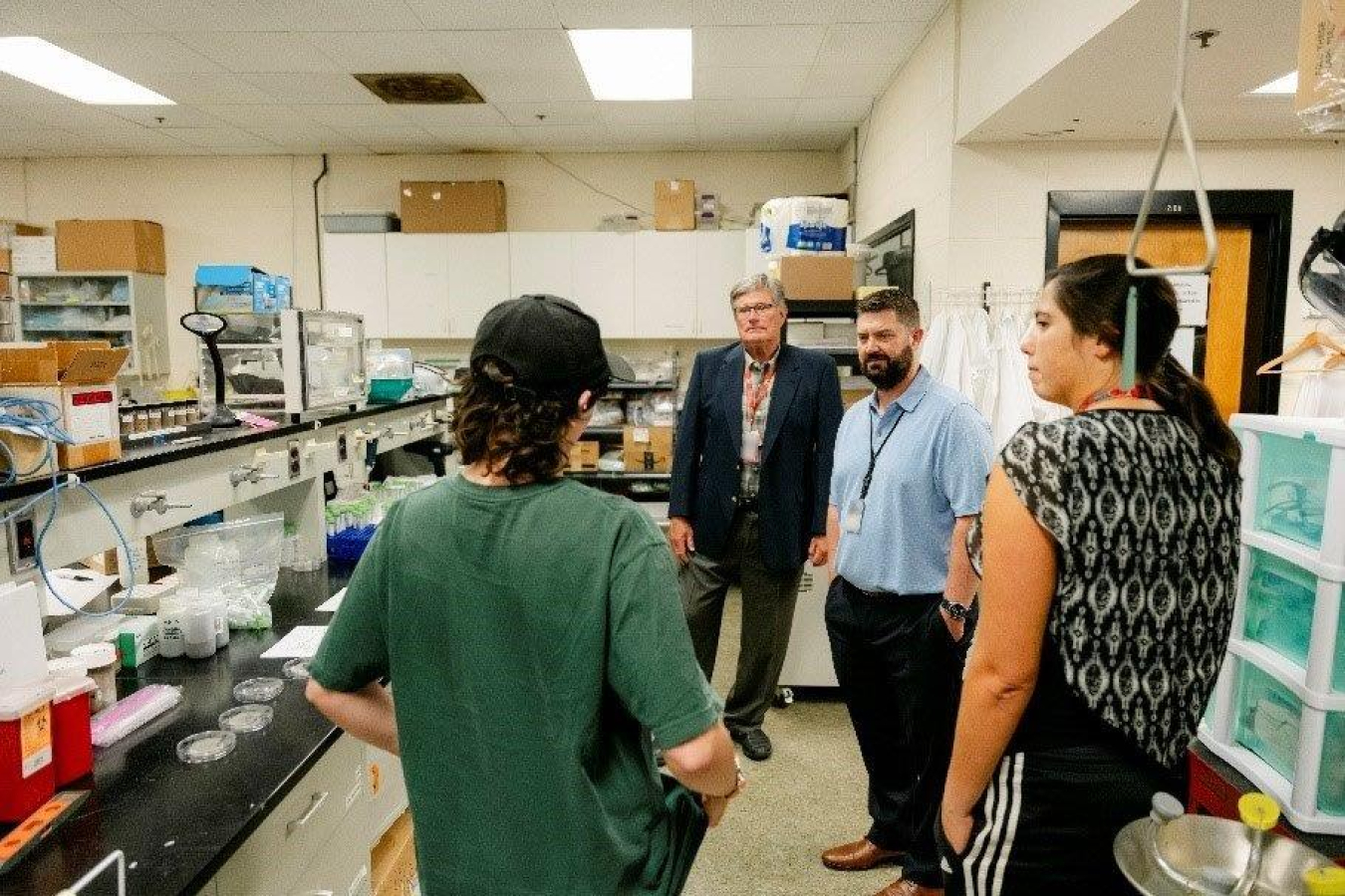A person engages with laboratory staff and students. 