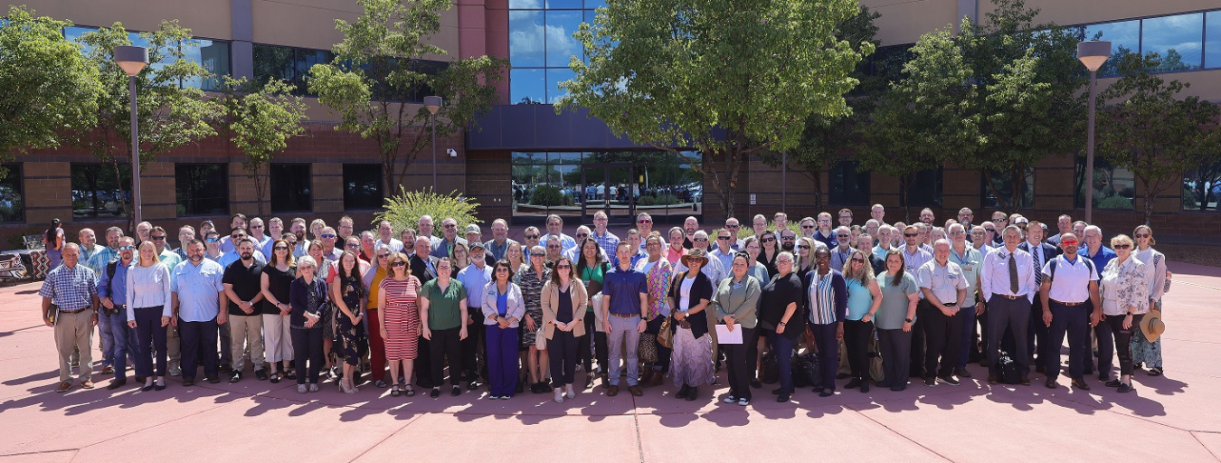 A large group of people pose for a photo outside of a building