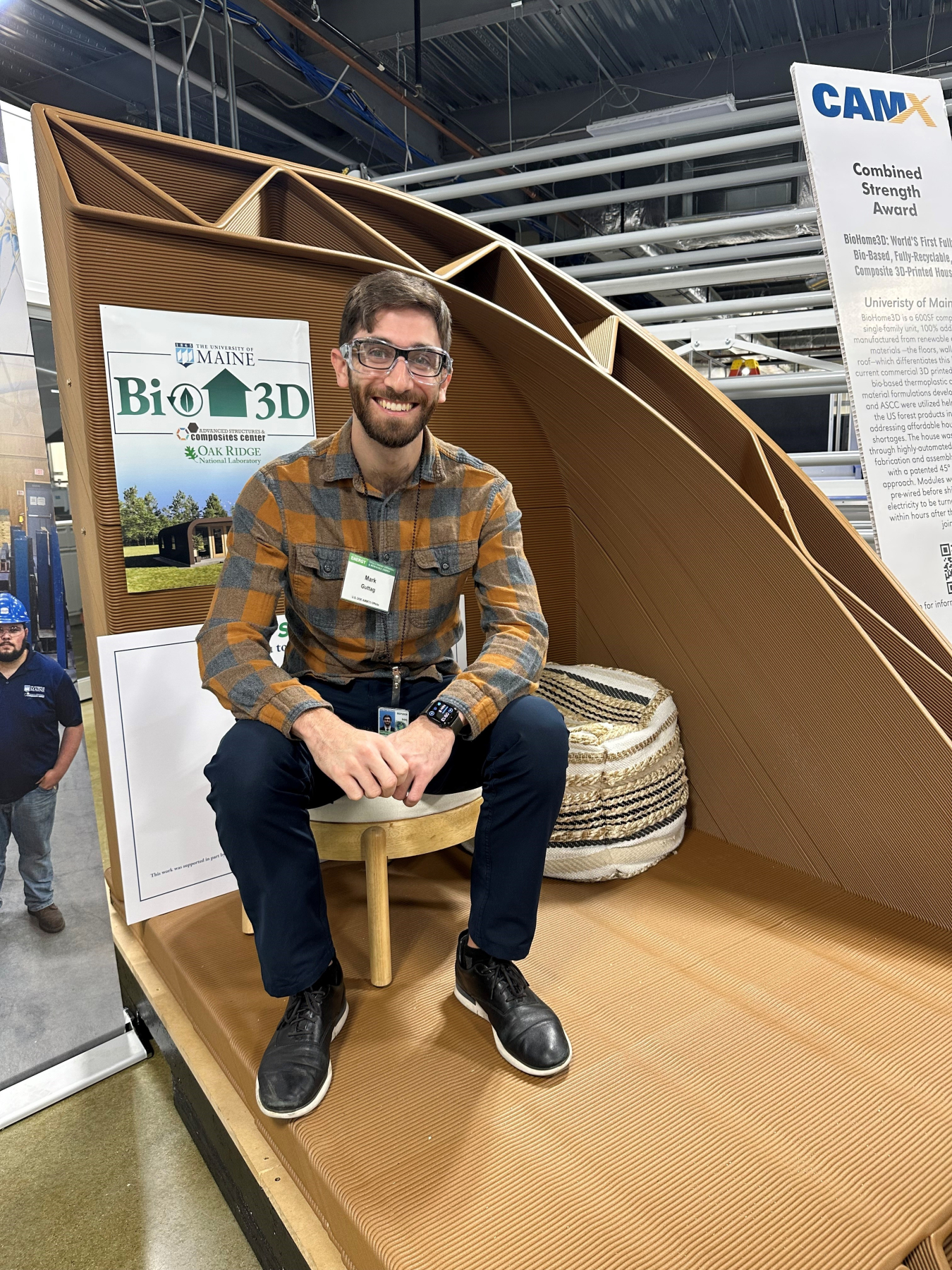 A person sitting in part of a 3D printed home in a warehouse