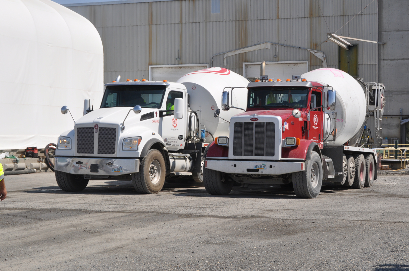 Two large tanker trucks parked outside of a facility building