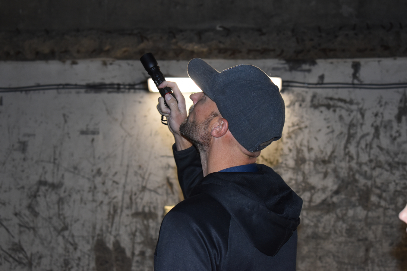 A man stands in a dark room and holds a flashlight upwards