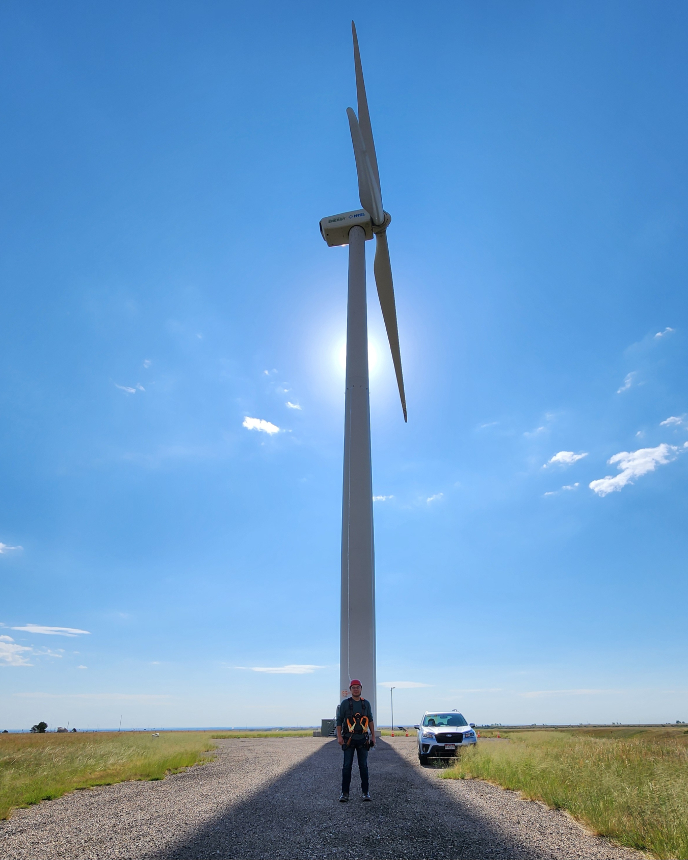 Isaac Marchand standing in front of a tall wind turbine