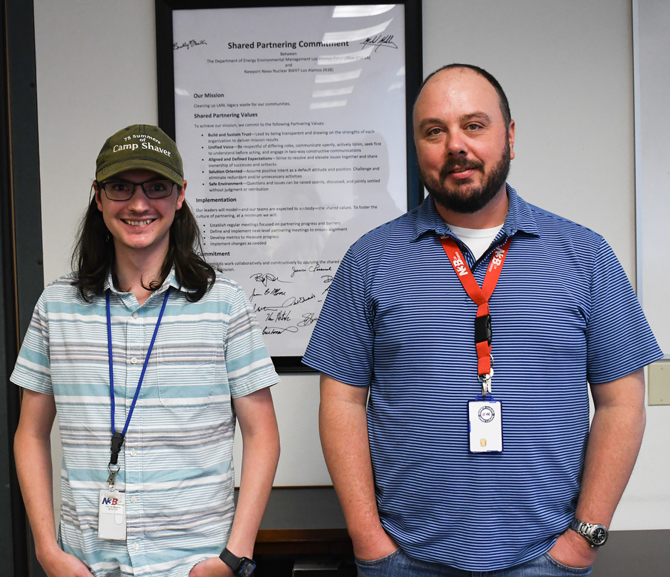 Two individuals stand beside a poster board and smile