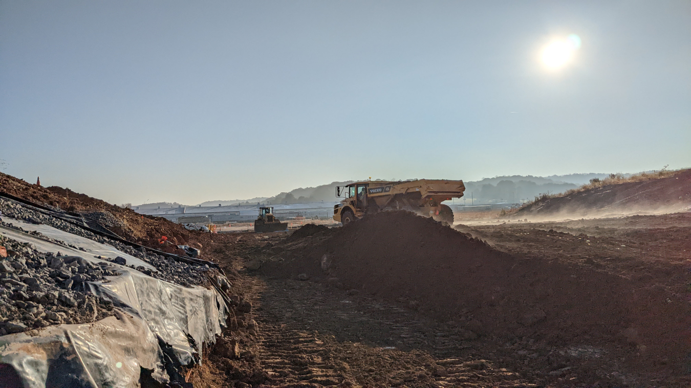 Two yellow work machine vehicles in a large dirt area