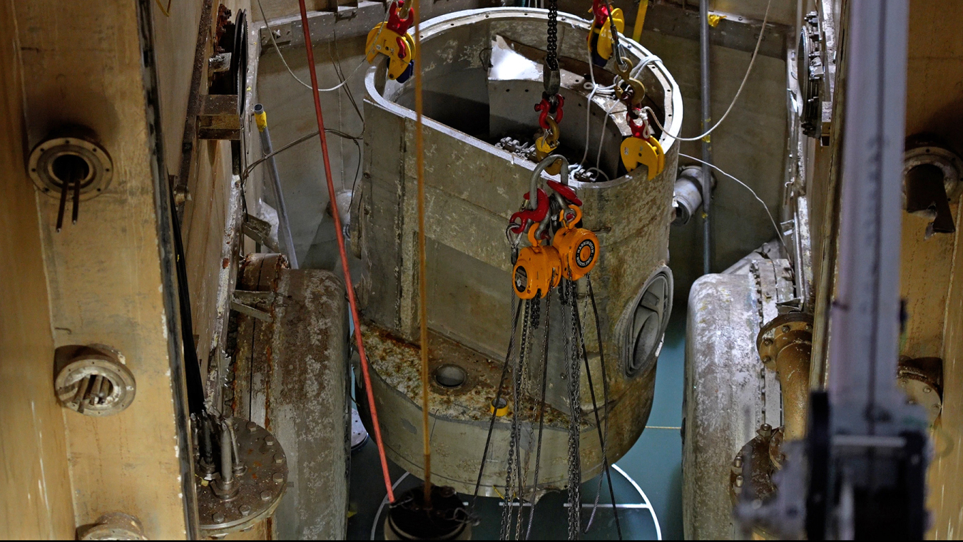 An up close shot of a reactor being lifted up attached to chains