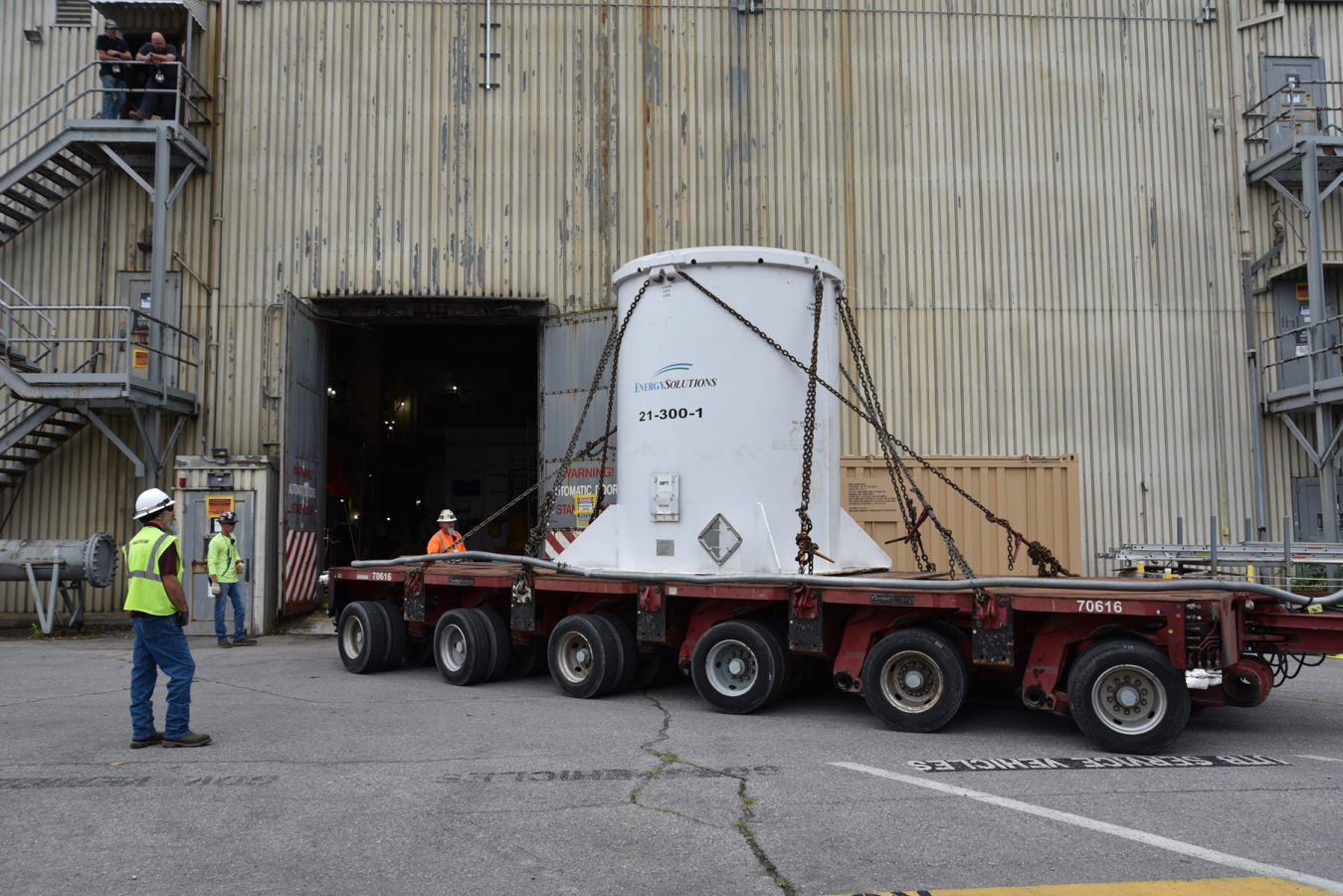 A white reactor tank on the back of a tractor trailer truck being prepared for shipment