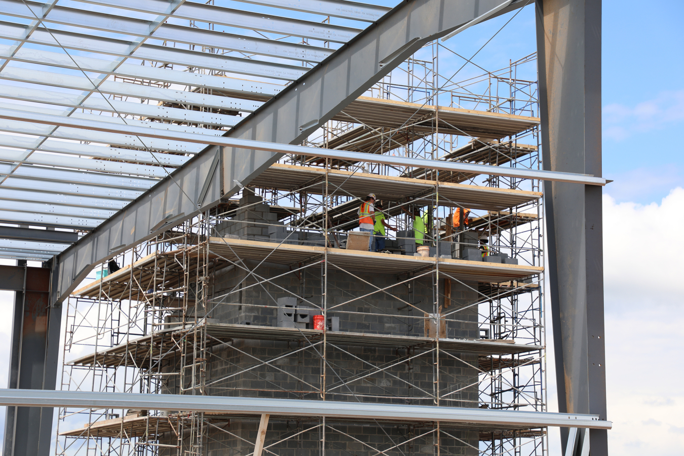A zoomed in view of a group of workers up on a platform performing construction work on the structure