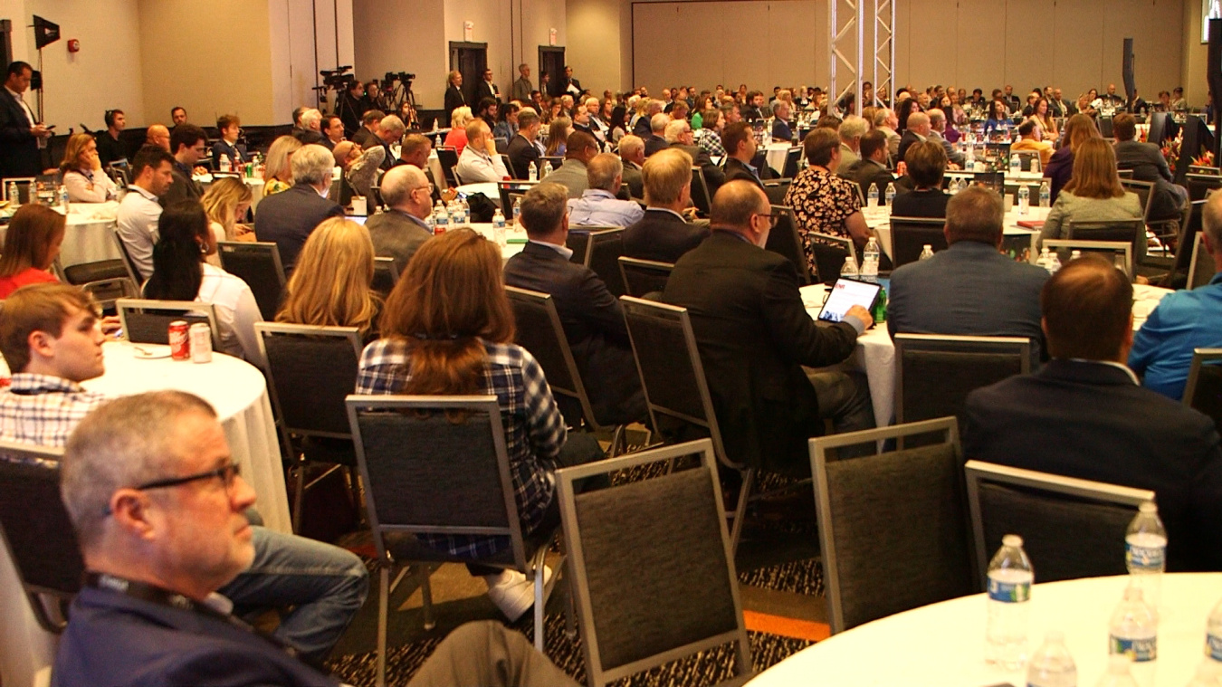 A large conference room full of people sitting at round tables