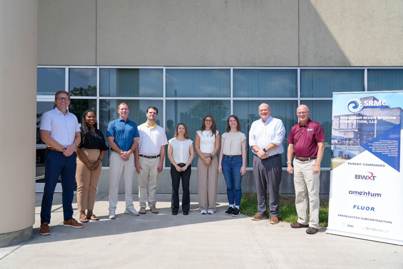 A group of people stand outside a building and pose for a picture