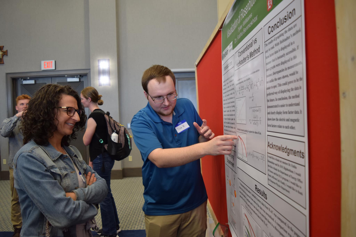 Tyler Williams discussing his poster with a passerby at the research symposium