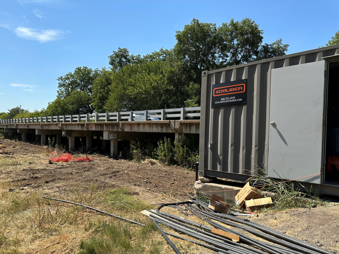 A bridge with a truck, pipes, and shed nearby.