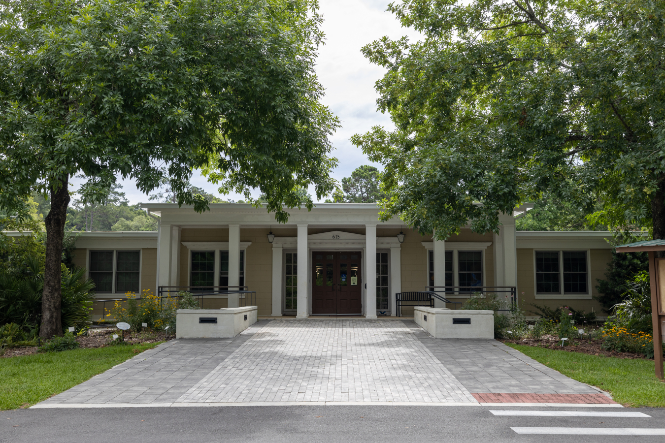 Image of the front of a building with landscaping and trees.