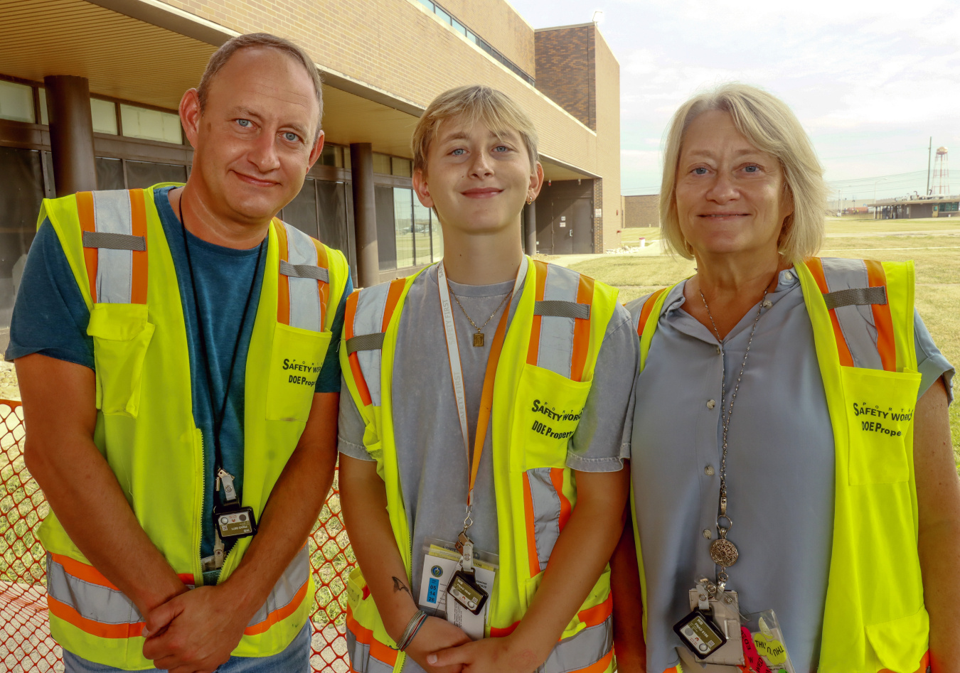 Two parents pose for a picture with their son, they all are wearing yellow safety vests