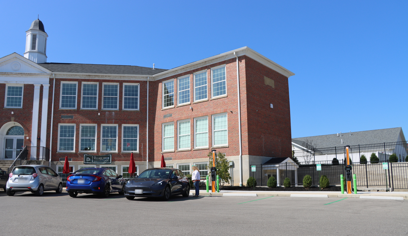 A large brick building with electric vehicle chargers in the parking lot 